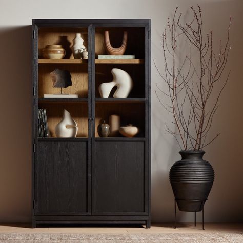 Matte black drifted oak frames lighter interior shelving for subtle but striking contrast. Glass doors allow for prized possessions to dazzle on full display while spacious cabinets add out-of-view storage. Panel Glass Door, Glass Door Cabinet, Bookcase With Drawers, Cabinet Finishes, Frame Light, Glass Cabinet Doors, Door Cabinet, Black Cabinets, Kiln Dried Wood