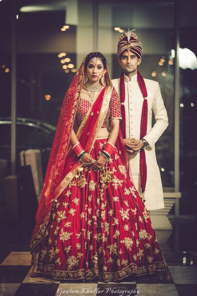 Bridal Wear - Bride in a Red Big Flare Lehenga | WedMeGood | Red Bridal Lehenga with Golden Embroidery and Double Dupatta, Groom in a Beige Sherwani with Red Safa  #wedmegood #indianbride #indianwedding #lehenga #bridal #red #coupleshot #candidcouple Bridal Lehenga Images, Sabyasachi Lehenga Bridal, Sabyasachi Bridal, Indian Groom Wear, Bridal Lehenga Designs, Indian Bridal Lehenga, Designer Bridal Lehenga, Bridal Lehenga Red, Red Lehenga