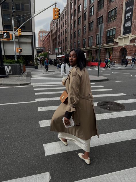 Young black woman crossing the cross walk in New York City wearing a beige trenchcoat and beige satin maxi skirt with beige ballet flats looking back at the camera while crossing the road Dress With Trench Coat, Styling A Trench Coat, Casual Trench Coat Outfit, White Satin Skirt, Trench Outfit, Satin Slip Skirt, Spring In New York, Velvet Style, Trench Coat Outfit