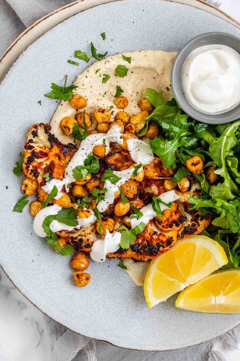 This roasted harissa cauliflower recipe is a must-try! Cauliflower steaks are coated in spicy harissa paste and roasted until tender and golden brown. Serve with homemade hummus, a tahini sauce drizzle, and crispy chickpeas. The result is a dish that's packed with flavor and perfect for satisfying your cravings. Whether you're a vegetarian looking for a hearty main course or just want a tasty side dish to accompany your meal, these roasted cauliflower steaks are sure to hit the spot. Vegetable Dinner Recipes, Harissa Cauliflower, Veg Pulao Recipe, Vegetable Recipes Dinner, Banana Food, Vegetarian Dinner Recipes, Roasted Cauliflower Steaks, Curried Lentil Soup, Hummus Ingredients