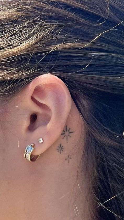 Behind-the-ear tattoos are both discreet and stylish. This hidden location is perfect for small dainty tattoos, whether you choose a star, moon, or tiny initial. The placement adds a touch of mystery, as it’s often only visible when you want it to be.  The behind-the-ear location is a great option if you’re looking for something subtle but meaningful. The small surface area ensures that the design remains delicate and understated, yet it still makes a statement when seen. Star Tat Behind Ear, Small Star Tattoo Behind Ear, Subtle Ear Tattoo, Being Ear Tattoo, Small Tattoos Ear Ideas, Tattoo Star Behind Ear, 3 Hearts Behind Ear Tattoo, Behind Ear Tattoo Fine Line, Small Moon Tattoo Behind Ear