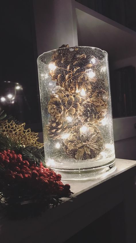 Just 3 items and a few easy steps: 1. Find a glass vase or votive that you like that matches your decor. 2. Get fairy lights - these are from the Target $5 below section. 3. Find pine cones or other decorative filler. I prefer scented pine cones. 4. Wind the fairy lights around the each pine cone and place into the vase. Continue until it is full. Christmas Baubles In Glass Vase, Fairy Lights Centerpiece Ideas, Pinecones In Vase, Fairy Lights In Clear Vase, Fairy Lights In Vase, Pine Cone Vase, Christmas Glass Vase Decor, Pine Cone Centerpiece Wedding, Glass Vase Filler Ideas Christmas