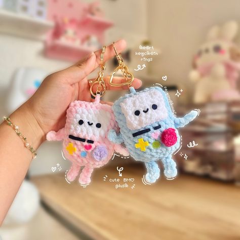 "These super adorable BMO inspired keychains make the cutest accessories! Each keyring features a lobster clasp & the cutest heart ring. This adorable crochet plush is perfect for decorating your bags, or gifting to someone special this holiday season! ♥︎ Every plush is handcrafted with love in a smoke-free & pet-free environment.  ꒰ Size & Materials ꒱ ➳ Size: approximately 4\" x 3\" ➳ made with 100% polyester yarn, poly-fil stuffing & felt details  ꒰ Care Tips ꒱ ➳ Do not machine wash or tumble dry. Spot cleaning is highly recommended, however if needed, hand wash gently with warm water and air dry. ➳ Please handle your plushies with love & care. If your plush contains safety eyes, or any other small accents such as beads, buttons, etc. it may not be suitable for small children as they may Bmo Crochet, Adventure Time Bmo, Amigurumi Keychain, Keychain Pattern, Crochet Plushies, Crochet Keychain Pattern, Crochet Plush, Crochet Business, Adorable Crochet