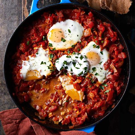 Shakshuka is a veggie-packed meal featuring eggs cooked in a mixture of tomatoes, onions, peppers and spices. It's typically served in North Africa and the Middle East for breakfast or lunch. Whole Wheat Pita, Spicy Tomato Sauce, Idee Pasto Sano, Mediterranean Diet Recipes, Iron Skillet, Stuffed Sweet Peppers, High Fiber, Mediterranean Diet, Mediterranean Recipes