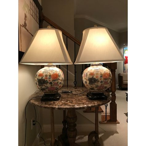 This distinctive pair of table lamps (sold as a set of two) feature beautiful Chinese jars of beige crackleware with gilt, blue, pink, brown, and orange painted floral porcelain; brass coin-style finial, harp and hardware; polished, carved wood bases; and off-white pleated lamp shades. The fixtures are wired to accommodate three lighting settings. Chinese Lamps, Pleated Lamp, Floral Lamp, Pleated Lamp Shades, Brown And Orange, Painted Table, Brown Floral, Harp, Lamp Shades