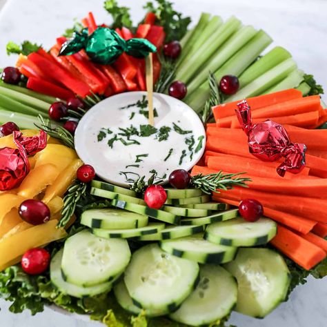 Make this simple Christmas wreath appetizer. This easy, festive Christmas Veggie Tray idea for holiday parties can be made ahead and is always a hit on an appetizer table. This vegetable charcuterie board includes: Red peppers, celery, carrots, cucumbers, yellow peppers, rosemary, cranberries, blue cheese or ranch dress, cilantro, and a few Christmas candies. | sipbitego.com Vegetable Charcuterie Board, Vegetable Charcuterie, Christmas Wreath Appetizer, Wreath Appetizer, Christmas Veggie, Simple Christmas Wreath, Christmas Veggie Tray, Appetizer Table, Ranch Dress