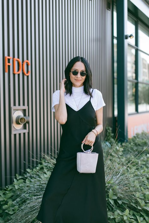 Style blogger Lilly Beltran wearing a black slip dress with a white t-shirt and white sneakers for a 90's inspired look. Slip Dress With Tee Shirt, White Tee Under Dress Outfit, Long Dress And Shirt Layer Outfit, White T Shirt Under Dress, Tank Dress With Shirt Under, T Shirt With Dress Over It, Black Dress With White Shirt Underneath, Long Dress With Shirt Underneath, Dresses With Tshirts Under