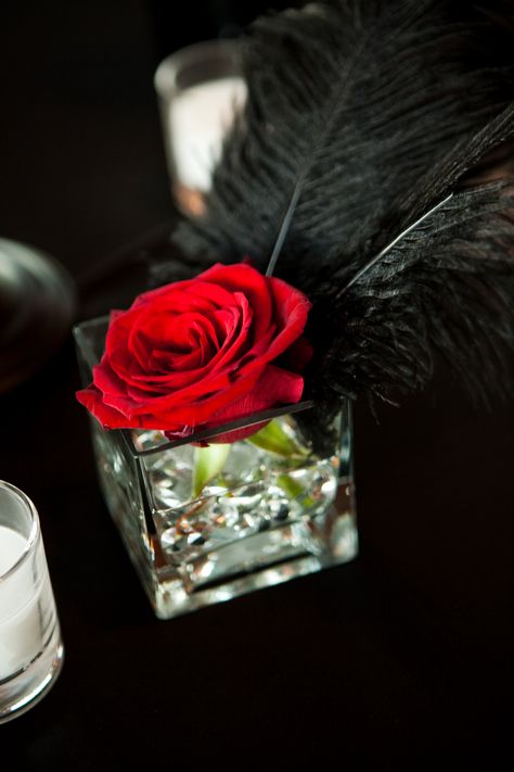 wedding centerpiece singe red rose.. kind of like the feather touch too Feather And Roses Centerpieces, Rose And Feather Centerpiece, Mascarade Table Centerpieces, Black And Red Table Centerpieces, Red And Black Feather Centerpieces, Red Feather Centerpieces, Red And Black Flower Centerpieces, Red Black And Gold Wedding Centerpieces, Black White Red Gold Party Centerpieces