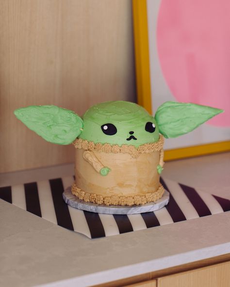 Adorable baby Yoda cake with big green candy chocolate ears and a huggable face and tiny little piped buttercream arms, sitting on a buffet. Yoda Cake Tutorial, Grogu Cake, Homer Simpson Cake, Chewbacca Cake, Heart Cake Recipes, Baby Yoda Cake, Cute Cake Designs, Simpsons Cake, Coco Cake