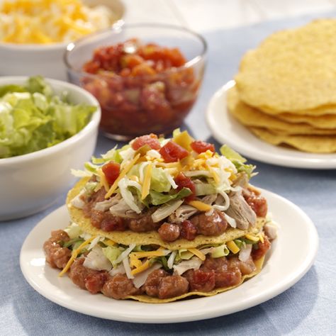 Tostada shells with layers of refried beans, chicken, lettuce, cheese and tomatoes Tostada Stack, Stack Recipes, Tostada Shells, Stacked Enchiladas, Mexican Food Recipes Appetizers, Tostada Recipes, Ready Set Eat, Mexican Appetizers, Spanish Dishes