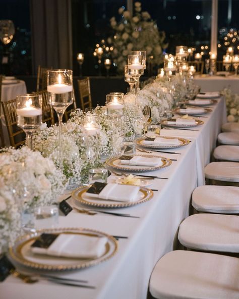 Transform your reception into a regal affair with intricate gold tablescape details. White florals, statement candles and the gold accents create an ambiance of opulent elegance. ✨ #weddinginspirations #weddingdesign #weddingtable #tablescape #weddingreception #nycwedding #bride Reception Table Decorations Candles, Elegant Outdoor Wedding Reception Table Arrangements, Classic Elegant Wedding Table Setting, Timeless Wedding Tablescape, White Wedding Design, Neutral Wedding Decorations Receptions, White Floral Wedding Table Decor, Wedding Themes White And Gold, White And Gold Wedding Aesthetic