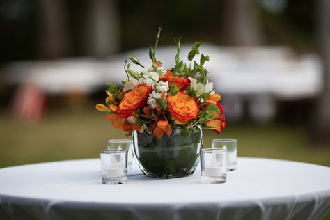 Orange, White & Green Flowers set in Small Glass Vase on top of Highboy Cocktail Table Orange Green And White Floral Arrangements, Orange Flowers Table Decor, Yellow White Orange Flower Arrangements, Green And White Cocktail Table Flowers, Orange Yellow Green Flower Arrangement, Short Glass, Small Glass Vases, White Flower Arrangements, Green Flowers