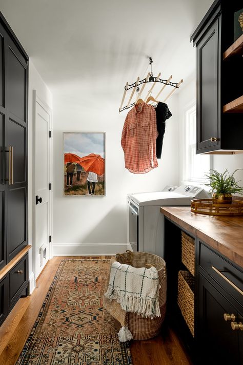 Black cabinetry paired with wood and neutral walls for a dynamic laundry room Natural Wood Cabinets Laundry Room, Dark Small Laundry Room, Laundry Room Wood Cabinets, Laundry Room Moody, Laundry Room Black Cabinets, Black Laundry Room Cabinets, Moody Laundry Room, Black Laundry Room, Wood Laundry Room