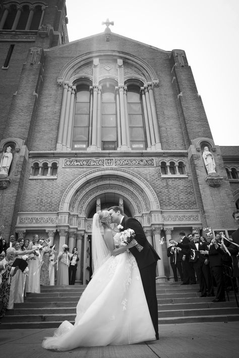 Black and white moment of a bride and groom kissing outside a church after their wedding. The bride is adorned with a beautiful long veil, while friends and family cheer in the background with streamers on sticks. Captured by photographer Jonathan Koslen of New Image Photography Photojournalism Wedding Photography, Church Wedding Pictures, Catholic Church Wedding Photos, Timeless Editorial, First Kiss Wedding, Church Wedding Photos, Church Wedding Photography, Bride Groom Photoshoot, Black And White Wedding Photos