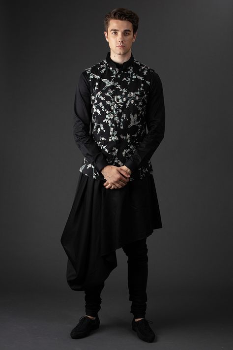 For the new age groom; a classic bandhgala elevated with intricate embroidery reminiscent of the fantastical creatures of flight, engineered with intricate sterling zari. The jacket is paired with a black draped  kurta with an asymmetric hemline. This look is befitting for a sangeet, finish with a churidar, velvet loafers and sleek pushed back hair #GauravGupta #GauravGuptaMan #GGMan #MensFashion #Menswear #OccasionWear #GGWedding #GGGroom #Groom Drape Kurta For Men, Black Dress For Men, Fitted Black Bandhgala With Traditional Drape, Black Kurta With Nehru Jacket For Men, Embroidered Black Bandhgala With Traditional Drape, Traditional Drape Black Kurta For Groom, Black Kurta Pajama Men, Black Kurta Pajama Men With Jacket, Semi-stitched Black Bandhgala For Festivals