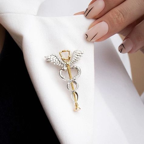 Find a lot more medical pins and nurse brooches in our Shop! https://www.etsy.com/shop/OrbitalEdge These pins are excellent thank you gift for doctors, medical students, nurses, and healthcare professionals. This caduceus brooch featuring a stethoscope is a stylish complement to everyday wear. The pin is available in 2 variants; gold and silver tones. This medical pin is made of plated stainless steel (not an enamel pin) an perfect gift for healthcare workers.  FREE SHIPPING: We offer free shipp Resident Doctor, Doctor Jewelry, Medical Pins, Medical Quotes, Nurse Jewelry, Medical Student Motivation, Nursing Pins, Medical Jewelry, Medical School Inspiration