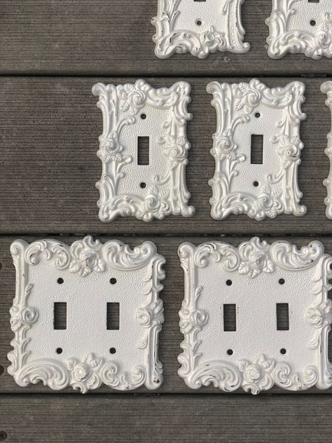 Sold separately - see dropdown menu for options.  Currently 9 available - metal Vintage ornate light switch covers / outlet covers - all painted satin heirloom white (slight off white) and lightly distressed throughout.  Largest one is marked 1967 American Tack & Hardware Co.  others are marked Edmar and AmerTac. No screws included. Please note I use recycled packaging and materials for shipping. Iron Family, Triple 6, Vintage Light Switches, Decorative Light Switch Covers, Wall Decor Lights, Vintage Hardware, Light Switch Plate Cover, Light Switch Cover, Switch Plate Covers