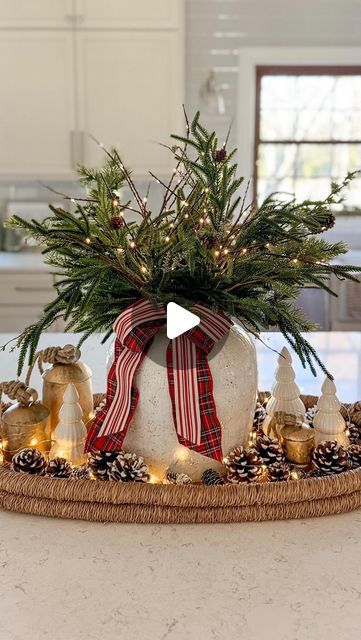 Jenny Brooks • Bloom Interior Designs on Instagram: "🎄✨This easy holiday tray is the perfect addition to your kitchen island, dining table or entryway…

Comment HOLIDAY and I’ll send you a link 🔗 with all the details for this centerpiece idea! You can also shop this post in the LTK link in my bio. 

I love this centerpiece with Norfolk pine stems, lighted twigs, antique bells & pinecones all wrapped up with a pretty bow! 

•SAVE• for later! 🎀

#christmasdecor #christmasideas #christmasdecorating #holidayhome #amazonhomefinds #christmasvibes #ballarddesigns #arhausinmyhouse #christmashome #centerpiecesideas #christmasinspo #ltkhome" Christmas Bell Centerpiece, Christmas Centerpiece For Island, Decorating Kitchen Island For Christmas, Christmas Decor Ideas For Kitchen Island, Christmas Island Centerpiece Ideas, Christmas Island Decor, Kitchen Island Christmas Decor Ideas, Island Centerpiece Ideas, Kitchen Island Decorating Ideas