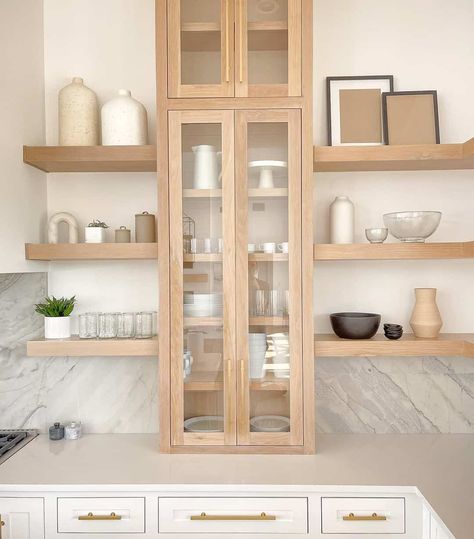 Employ a unique shelving design by applying a light oak note to create built-in stands and a glass cabinet. This installation lets you showcase your favorite farmhouse kitchenware and décor neatly and beautifully. The addition of simple warm tones creates a lovely vibe to the space. Kitchen With Oak Cabinets, Light Oak Cabinets, Unique Shelving, Glass Kitchen Cabinets, White Shiplap Wall, Natural Wood Flooring, Unique Shelves, Oak Kitchen Cabinets, Shelving Design