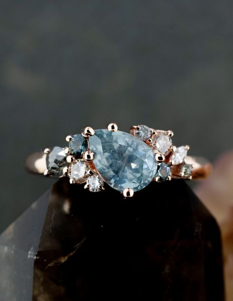 A one-of-a-kind, handcrafted cluster engagement ring, made with the combination of sapphires and diamonds. The Rebeku was designed to be perfectly imperfect, as a large part of marriage is accepting the imperfect. Not wanting a diamond center stone, we sourced this 100% ethical Montana sapphire and set it at an angle to add to the unique asymmetry of the piece. #uniqueengagementring