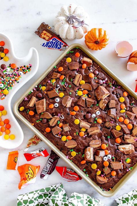 If you're a fan of brownies, you have to try this fun Halloween version. A brownie mix is paired with coconut oil, eggs, cold water and dark chocolate chips, along with leftover Halloween candies chopped into pieces. Anything the trick or treater's bring home is fair game for these brownies - chocolate bars, candy corn, marshmallows, boiled candies, and more! Use any chocolate bars or candies you want. Well, except gum maybe! These brownies are a great dessert the whole family will really love! Recipes With Brownie Mix Boxes Candy Bars, Desserts With Candy Bars, 3 Layer Brownies, Recipes With Halloween Candy, Recipes For Leftover Halloween Candy, Leftover Candy Bar Recipes, Halloween Candy Brownies, Halloween Candy Desserts Leftover, Recipes With Leftover Halloween Candy