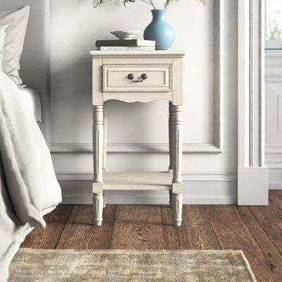 This 1-drawer nightstand brings French country style to your bedroom. Made from solid pine wood, it has a purposefully distressed finish that gives it a well-loved look. We love this bedside table’s antique-inspired details, from its scalloped apron to the fluting on its turned post legs. The single-paneled drawer has a contrasting dark bronze-colored handle; together with an open lower shelf, it offers plenty of space to tuck away your nighttime essentials. Hand-curated by Kelly Clarkson. Color Mismatched Bedside Tables, Parisian Nightstand, Blue Bedside Table, French Nightstand, Bed Essentials, Molding Detail, Tall Nightstand, Small Nightstand, Tall End Tables