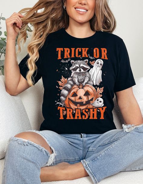 🦝🎃 Monday Mood: Trick or Trashy! 🎃🦝 Start your week with a dash of humor and a whole lot of spooky vibes! Our "Trick or Trashy" T-shirt is here to bring some mischief to your Monday. Featuring an adorable raccoon perched on a Halloween pumpkin with two cute ghosts in tow, this tee is perfect for all you coffee-loving, quirky souls out there. ☕👻 Whether you're gearing up for spooky season or just need a little Monday pick-me-up, this playful shirt is a must-have. And guess what? We're giving... Raccoon Halloween, Quirky T Shirts, Trick Or, Cute Ghosts, Halloween Tshirt, Coffee Shirt, Costume Parties, Fall Coffee, Autumn Coffee