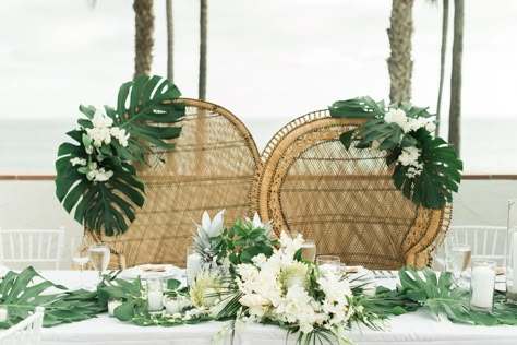 Tropical Wicker Sweetheart Chairs with Monstera Leaves Beach Wedding Color Palette, Sweetheart Table Chairs, Tropical Wedding Centerpieces, Peacock Chairs, Tropical Wedding Decor, Beach Wedding Colors, Tropical Florals, Sweetheart Table Wedding, Peacock Chair