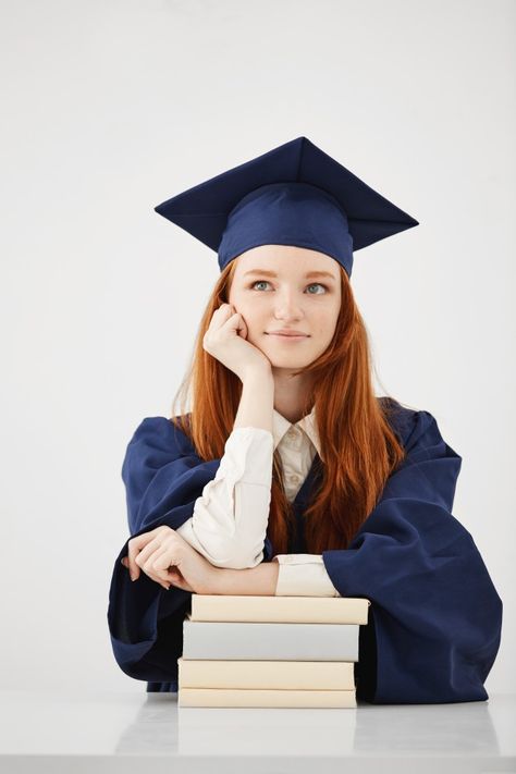 Dreamy graduate woman smiling thinking sitting with books over white surface Free Photo