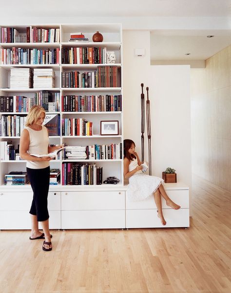 The main living room, separated by a freestanding wall, continues into an open study. The bookshelves, close to ten feet tall, are home to numerous architectural books, philosophy texts, and the literary work of Ayn Rand. Recessed speakers emanate music t Tall White Bookshelf, Tall Bookshelves, White Bookshelves, Free Standing Wall, Wood Bookcase, Storage Design, Home Library, Wall Shelves, Home Living Room