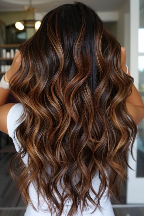 Woman with long, wavy brown hair with caramel highlights standing indoors. High Light Ideas For Brunettes, Caramel And Cinnamon Highlights, Dark Hair With Honey Balayage, Dark Brown Hair Highlights Caramel, Diy Caramel Highlights On Dark Hair, Ashy Chocolate Brown Hair Balayage, Asian Caramel Highlights, Balayage Hair Copper Caramel, Dark Brown With Honey Highlights