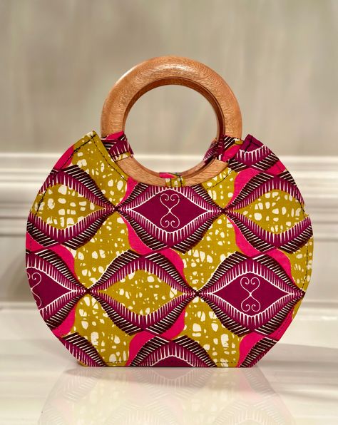 Our handmade hand bag with wooden handle is not big or too small. It’s just the right bag to fit your phone, wallet, and a few personal items. Lined with black fabric. Has an inside pocket. Zip to keep content intact. Wooden handle may vary from picture depending on piece shipped to you. Adepa is the top notch fabric in Ghana! DIMENSIONS;Length - 10 inch Width - 4 inchHeight - 8 inches (12” with handles) care : spot clean Wooden Bag Handles, Sequence Gown Styles, Sequence Gown, Wooden Handle Bag, Wooden Bag, African Crafts, Gown Styles, African Necklace, Printed Purse