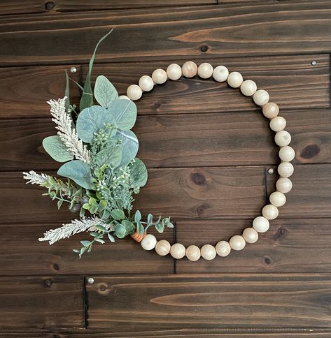 This handmade wreath is neutral toned with a split wood bead base and nature inspired embellishments. At 12 inches in diameter, it adds a soft, natural look to any space. A soft leather tie at the base of the greenery adds a subtle hint of color and boho style. Features: - Natural split wood beads (1 in diameter) - Faux greenery - Saw tooth hanger on back - Free Priority Mail Shipping! Please note: Although adhered to the wreath, the wood beads could be a choking hazard for small children so ple Eucalyptus And Pampas, Wood Bead Wreath, Bead Wreath, Leather Tie, Handmade Wreaths, Modern Farmhouse Decor, Pampas Grass, Soft Natural, Natural Look