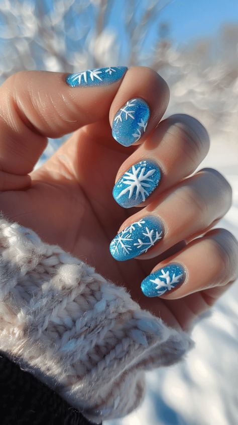 A manicured hand with icy blue nails with white snowflake designs representing Elsa from Frozen. Snowflake Nail Art Designs, Frozen Theme Nails, Frozen Nails Disney, Xmas Nails Snowflake, Winter Blue Nail Designs, Winter Disney Nails, Disney Winter Nails, Snowflake Nails Blue, Winter Nails With Snowflakes