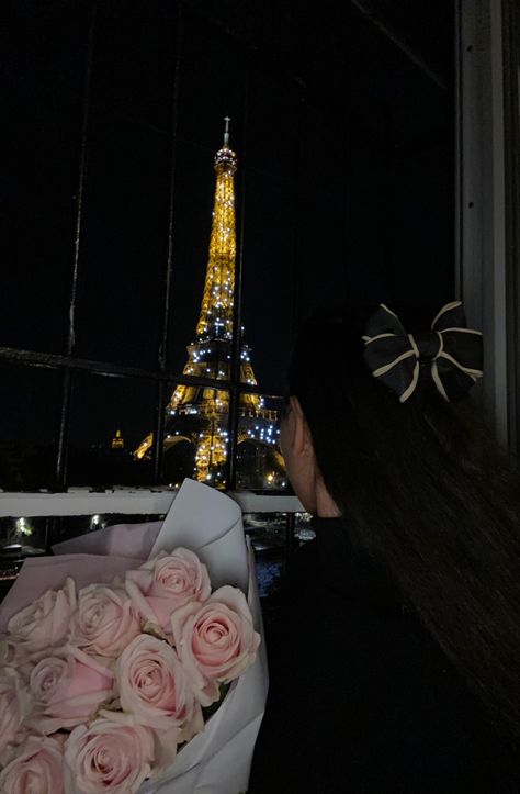 Girl sitting in front of Eiffel Tower at night holding pink roses with a beige and black bow in her hair Birthday In Paris Aesthetic, Paris Birthday Aesthetic, Eiffel Tower Photoshoot, Birthday In Paris, Parisian Birthday, Paris Photo Ideas, Bow Outfit, Night Paris, Paris Photoshoot