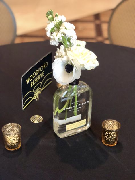 We used multiple bourbon bottles as vessels, for this great Gatsby inspired wedding. Speakeasy Wedding Centerpiece, Bourbon Event Decor, Bourbon Wedding Centerpieces, Bourbon Bottles Wedding, Bubbles And Bourbon Party, Whiskey Themed Centerpieces, Bourbon Wedding Decor, Whisky Bottle Centerpiece Wedding, Bourbon Party Decor