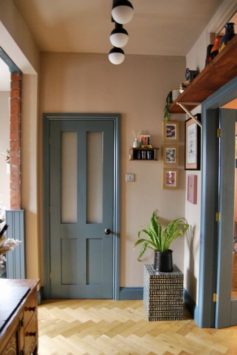 The doorway to a kitchen with a blue-trim accent next to a small gallery wall of framed art. Colour Door Frame, Low Ceiling Color Ideas, Eclectic Accent Wall Ideas, Blue Painted Interior Doors, Colorful Moldings And Trim, Teal Trim Interior, Creative Wainscoting Ideas, Small Hallway Color Ideas, Color Door Frame