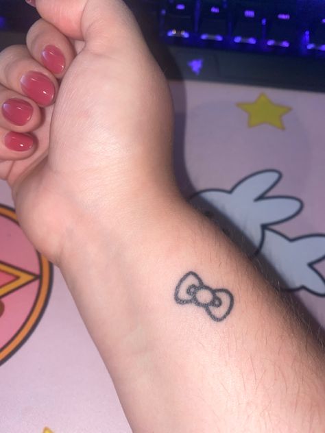 Hello Kitty’s bow tattooed in black ink on wrist Cute Hand Tattoos Small Simple, Hello Kitty Bow Tattoo, Stick And Poke Tattoo Ideas Simple, Simple Stick And Poke Tattoo, Tattoo Hello Kitty, Tatuaje Hello Kitty, Bow Finger Tattoos, Bow Tattoos, Bow Tattoo Designs