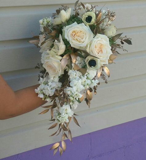 Cascade of white stock, cream roses, panda anenomes accented with gold foliage Bridal Bouquet With Gold Accents, Green White Gold Bouquet, Sage And Gold Wedding Bouquet, Gold And White Wedding Bouquet, White And Gold Flower Arrangements, White And Gold Wedding Bouquet, White And Gold Bouquet, Elizabethcore Aesthetic, Restaurant Flowers