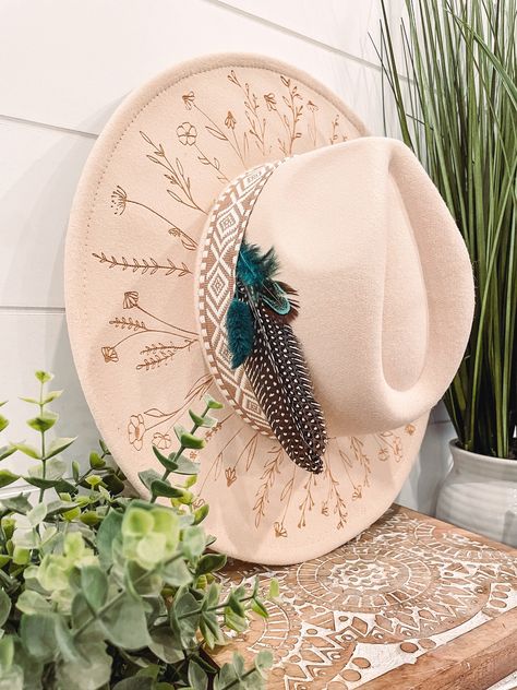 Wildflower Floral Burned Hat, Floral Engraved Cowboy Hat, Sunflower Hat, Sunflower Burned Fedora, Engraved Fedora, Engraved Felt Hat, Boho Hat Elevate your style with our beautifully engraved floral hats! If you want certain colors for the feather/flower detail, please leave a note at checkout. Bands and florals/feathers may shift or fall off during shipping. The hat has an adjustable band on the inside to fit many sizes. One size fits most adult heads. Decorated Felt Cowboy Hats, Hat Burn Designs, Custom Burned Felt Hats, Custom Cowboy Hat Ideas, Boho Wedding Hat, Diy Hat Band, Burned Hat Design, Boho Hats For Women, Hat Burning Ideas