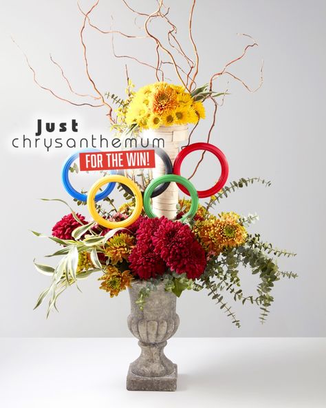 How are your national athletes doing? Show your support and celebrate the spirit of competition with stunning chrysanthemum designs! 🥇 Incorporate a winning element in your arrangements, like this one featuring the iconic Olympic rings. Bring the victory vibes into your store and cheer for our champions in style!  Design: student of Ecole Nationale des Fleuristes Olympic Centerpieces, Olympic Flower Arrangement, Olympic Wreath Craft, 1972 Olympics, Olympic Rings, Chrysanthemum, Intense Colors, How Beautiful, Florist