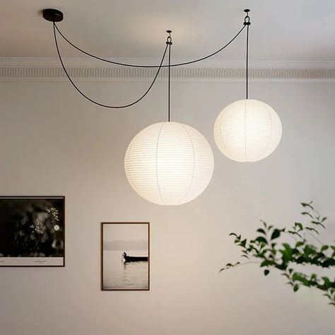 Illuminate your space with the timeless elegance of the Akari 55A Style Pendant Light. Inspired by traditional Japanese design, this pendant light features a delicate, spherical lantern made from handmade rice paper. Its soft, warm glow creates a serene and inviting atmosphere, perfect for any room in your home. Whether you're enhancing your dining area, brightening up your living room, or adding a touch of sophistication to your workspace, the Akari 55A effortlessly blends functionality with ae Paper Lantern Living Room, Parisian Terrace, Paper Lanterns Diy Hanging, Traditional Japanese Design, Hanging Paper Lanterns, Paper Balloon, Romantic Ambiance, Design Japonais, Hotel Lobbies