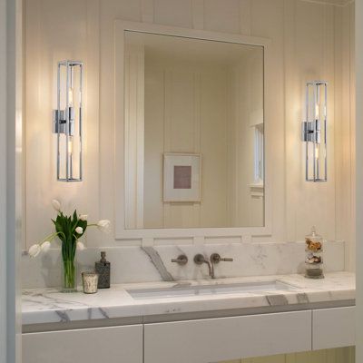 Balancing glam and modern style in equal parts, this 2-light vanity fixture brings a luminous look to your bathroom. It's made from metal and features a streamlined, open cage-like frame with crisp lines and a rectangular silhouette on a square backplate. Two sockets suit standard-size bulbs of up to 60W (sold separately) and expose the bulb for maximum brightness in your space. We recommend this fixture for dry locations only. Highlight: It's easy to pair with a dimmer switch, letting you set t Side Vanity Lights, Large Bathroom Mirror With Sconces, Vanity Wall Sconces Master Bath, Bathroom Vanity Lighting Side Of Mirror, Bathroom Vanity Wall Sconces, Bathroom Sconces Single Vanity, Bathroom With Sconces, Bathroom Mirror With Sconces, Sconces Bathroom Mirror