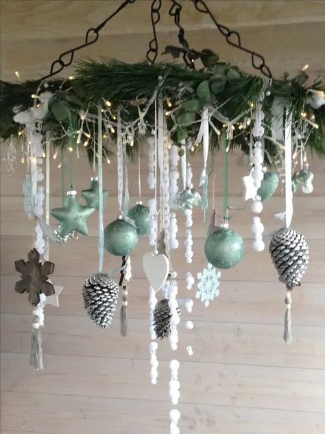 a Christmas chandelier with evergreens and greenery, lights, light green ornaments, wooden snowflakes and hearts and snowy pinecones Chandelier Christmas Decor, Xmas Ornaments Diy, Christmas Chandelier Decor, Christmas Chandeliers, Aesthetic Home Design, Christmas Shop Displays, Christmas Ceiling Decorations, Christmas Chandelier, Green Ornaments