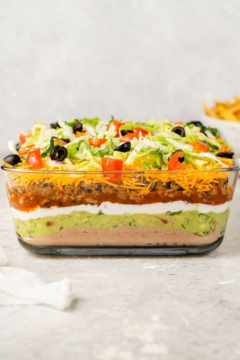 This Vegan 7-Layer Dip is the best cold vegan dip to serve on game days. Enjoy this layered fiesta dip with your favorite tortilla chips. Taco Meals, Gameday Snacks, Layered Dip, Vegan Tacos Meat, Vegan Easter Recipes, Appetizers Easy Dips, Dinner Board, Layered Dip Recipes, Homemade Refried Beans