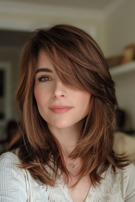 Smiling woman with shoulder-length brown hair in a light-colored shirt. Long Side Swept Bangs Fine Hair, Layered Hairstyles With Side Bangs, Face Frame Bangs Medium Hair, Hairstyles For Medium Length Hair With Side Bangs, Side Framing Bangs, Feathered Side Swept Bangs, Medium Length Haircut With Side Swept Bangs, Sweeping Fringe Mid Length, Side Parting Fringe