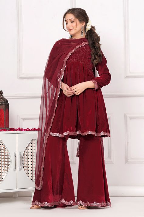 Our 3-piece maroon velvet suit set features an A-line kurta with a V-neckline and three-quarter sleeves. Complemented with Sharara pants with a partially elasticated waistband and a dupatta. Adorned with scalloped edge detailing, thread work, and sequins accents, this style is perfect for festive celebrations. Maroon Velvet Suit, Zodiac Gods, Kurti With Sharara, Wedding Guest Outfit Inspiration, A Line Kurti, Sharara Pants, Band Ideas, A Line Kurta, Velvet Suit