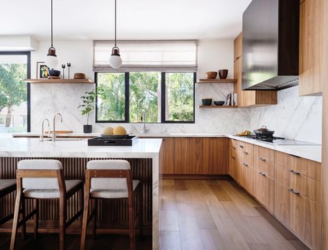 In the kitchen, plain-sliced walnut cabinetry by Henrybuilt nods to the home’s midcentury roots, as does the fluting on the island. To temper the wood, Sullivan chose heavily veined Calacatta Vagli marble from Da Vinci Marble, which also adds drama to the space. Allied Maker pendants illuminate Capo counter stools by Neri & Hu for De La Espada. Walnut And White Kitchen Modern, Walnut Floor Kitchen, Walnut Flooring, Midcentury Modern Kitchen, Modern Walnut Kitchen, Woodside Homes, Walnut Kitchen Cabinets, Modern Wood Kitchen, Walnut Kitchen