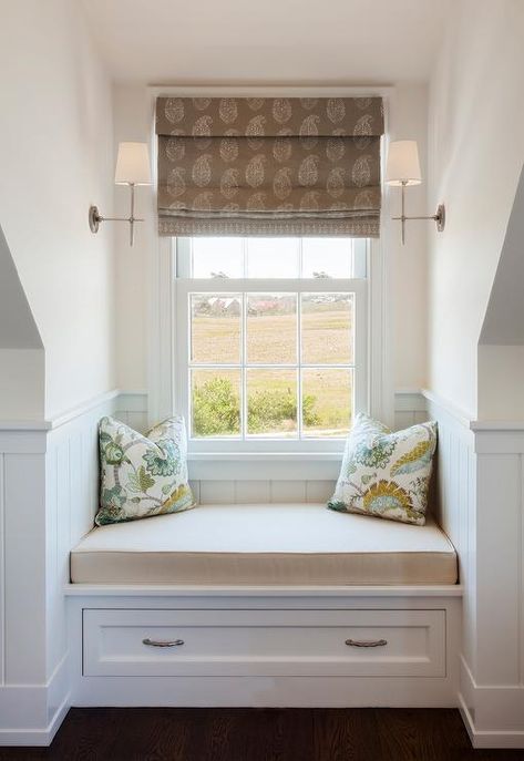 A brown paisley block print roman shade hangs from a window between facing Thomas O'Brien Bryant Sconces and over a white built-in window seat. Bedroom Window Alcove Ideas, Attic Bedroom Window Seat, Dormer Window Built Ins, Window Seat In Dormer, Dormer Window Storage Bench, French Country Bay Window, Window Seat With Sconces, Dormer Bench Seat, Dormer Window Seat Ideas