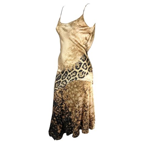 Presenting a stunning beige silk Roberto Cavalli slip dress. From the early 2000s, this gorgeous dress is covered in a tan abstract and leopard print. The dress features a scoop neckline, spaghetti straps, a flared hem, and a draped accent at the back. This sexy is constructed of luxurious silk that perfectly and gently reflects light. Approximate measurements: Size - S Bust: 24-26" Waist: 24" Hips: 28-30" Shoulder to hem: 50" 100% Silk Silk Dress With Leather Jacket, Slip Dress Jacket, Tyla Dress, Vintage Designer Dresses, 2000s Dresses, Vintage Roberto Cavalli, Animal Print Mini Dress, Vintage Dress Design, Roberto Cavalli Dress